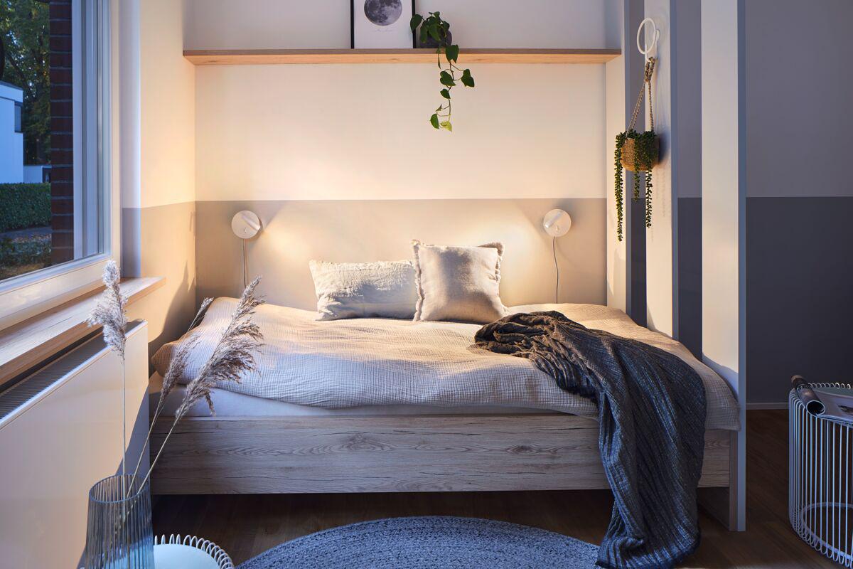 Cozy bedroom with wooden bed, beige bedding, and wall lamps providing warm ambient lighting