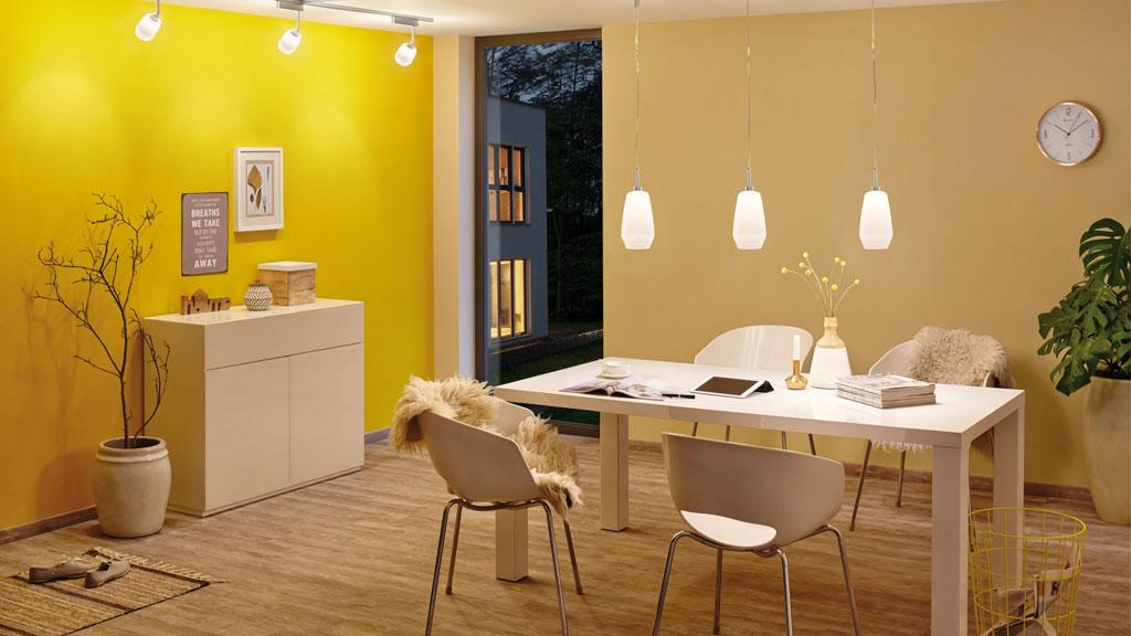 Dining room with white table, four chairs, and three hanging white pendant lights for modern lighting.