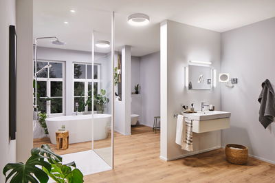 Salle de bain moderne avec baignoire autoportante, sol en bois et plafonniers LED blancs pour éclairage d'ambiance