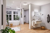 Modernes Badezimmer mit freistehender Badewanne, Holzfußboden und weißen LED-Deckenleuchten für Wohnraumbeleuchtung