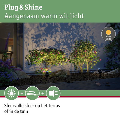 Buitenverlichting met warm wit licht verlicht groene struiken bij muur voor sfeervolle tuinverlichting