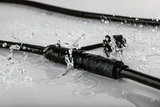 Black waterproof connector cable with water splashes, durable electrical accessory for outdoor use