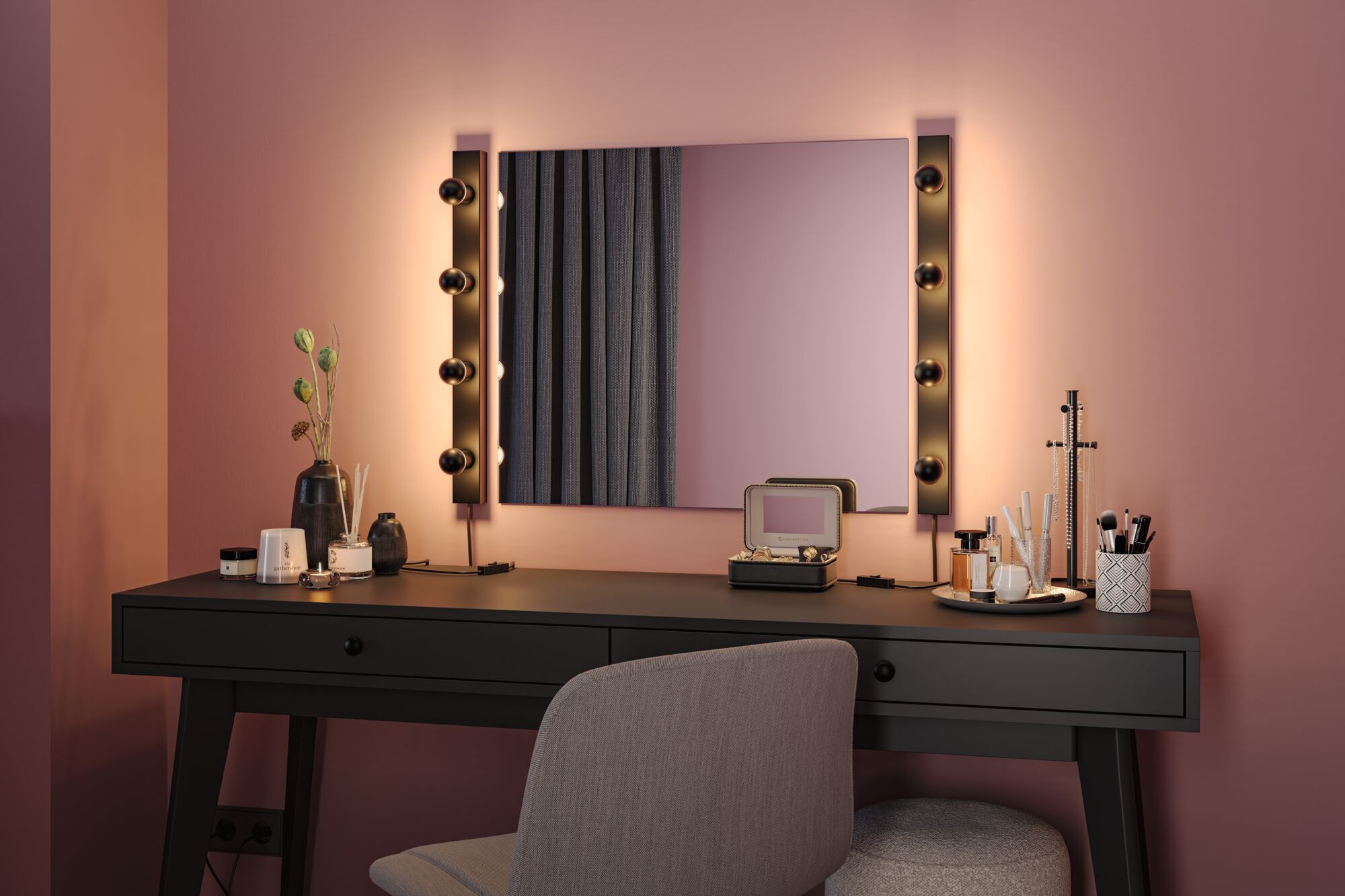 Coiffeuse noire avec miroir éclairé et mur rose pour un maquillage élégant et rangement cosmétique.
