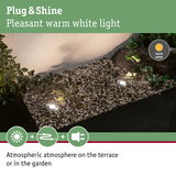 Grey LED recessed lights with warm white light create atmospheric garden lighting on gravel surface