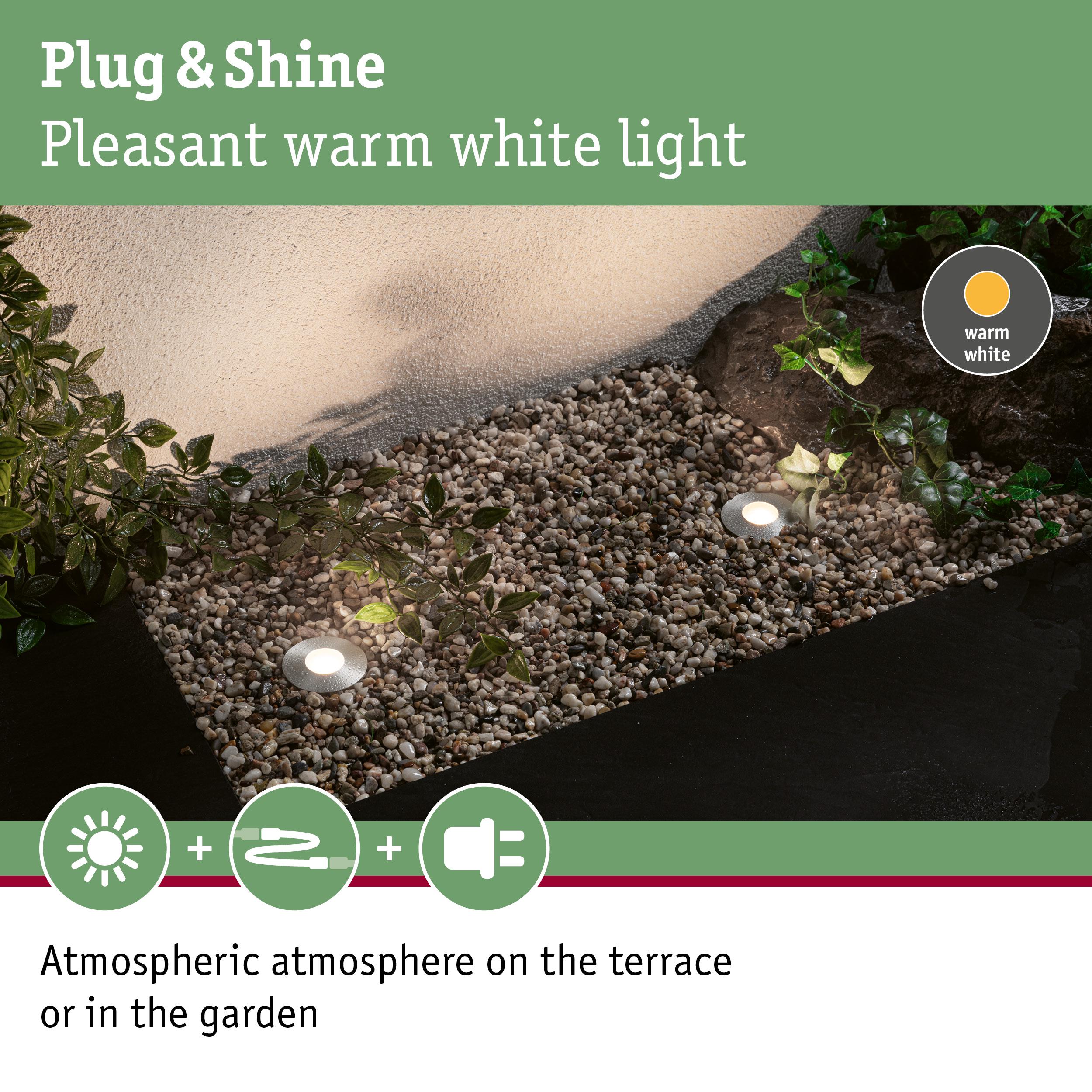 Grey LED recessed lights with warm white light create atmospheric garden lighting on gravel surface