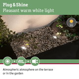 Grey LED recessed lights with warm white light create atmospheric garden lighting on gravel surface