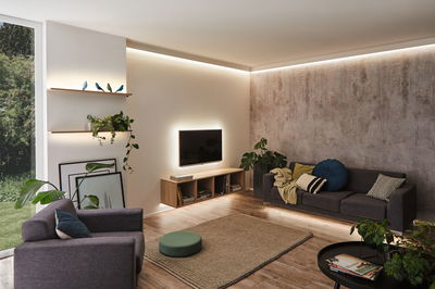 Modern living room with indirect LED lighting on ceiling, walls, and furniture creating cozy ambiance