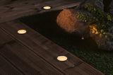 Round LED recessed lights with warm white glow in dark wooden terrace floor for outdoor lighting.