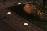 Round LED recessed lights with warm white glow in dark wooden terrace floor for outdoor lighting.