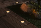 Round LED recessed lights with warm white glow in dark wooden terrace floor for outdoor lighting.