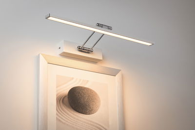 Modern white LED picture light with aluminum arm for wall mounting, providing ambient lighting.