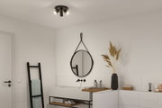 Modern bathroom with black ceiling light, round mirror, white sink and wooden shelf for bathroom decor