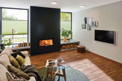 Modernes Wohnzimmer mit eingebautem Kamin, Holzlager und runden Deckenleuchten für gemütliche Beleuchtung