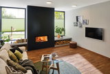 Modernes Wohnzimmer mit eingebautem Kamin, Holzlager und runden Deckenleuchten für gemütliche Beleuchtung
