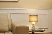 Beige Ledersofa neben schwarzem Glastisch mit weißer Keramiklampe und beigem Lampenschirm im Wohnzimmer