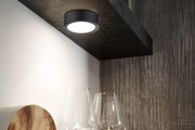 Runde schwarze LED-Deckenleuchte aus Metall mit warmweißem Licht über Gläsern in moderner Küche