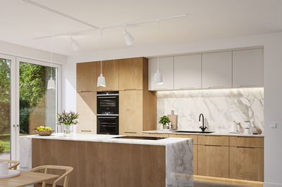 Moderne Küche mit Holzfronten, weißem Marmor und weißen Pendelleuchten für stilvolle Raumbeleuchtung