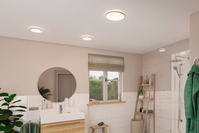 Salle de bain moderne avec plafonniers ronds diffusant une lumière blanche chaude et accents bois naturel.