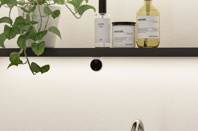 Black wall shelf with green plant and Meraki skincare products in white and yellow for bathroom decor