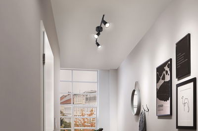 Schwarze LED-Deckenleuchte mit drei verstellbaren Spots in modernem Flur mit Wanddeko und Fenster.