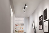 Black LED ceiling light with three adjustable spotlights in modern hallway with wall decor and window.