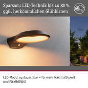 Schwarze LED-Außenwandleuchte mit warmweißem Licht an weißer Wand, energiesparende Beleuchtung
