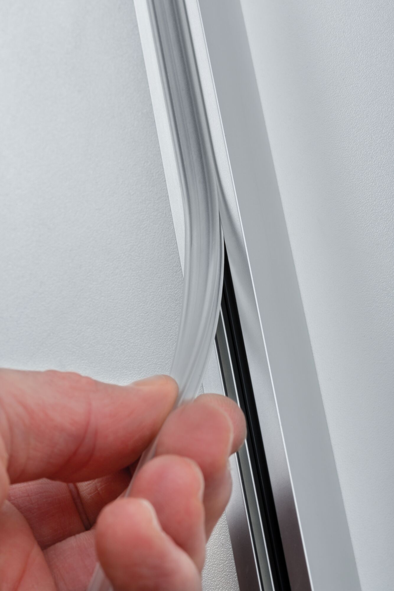 Hand holding transparent flexible LED strip next to silver aluminum profile for LED lighting