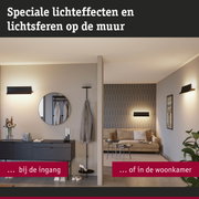 Modern woonkamer met beige bank en zwarte wandlamp die speciale lichteffecten op de muur creëert
