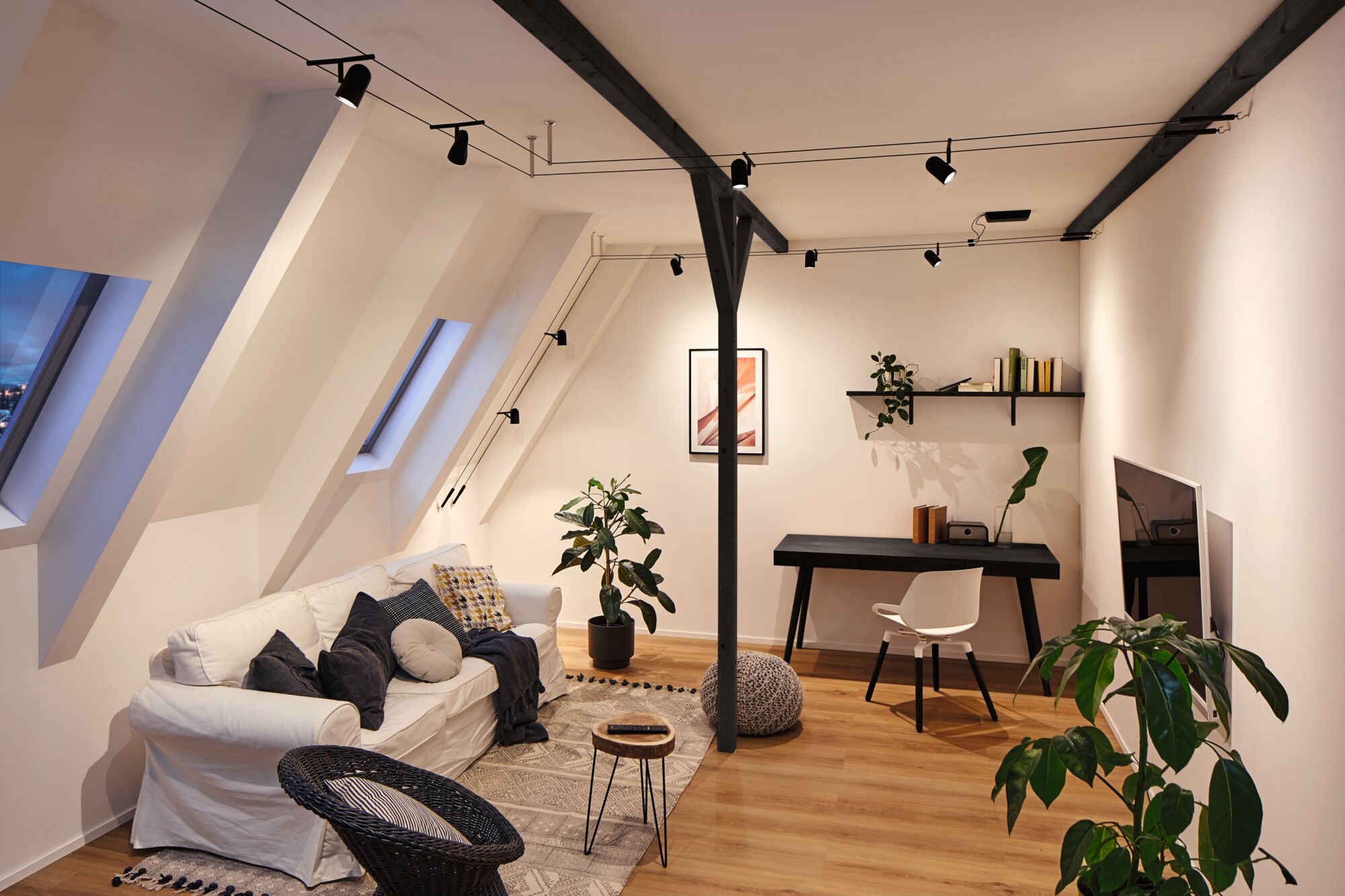 Moderne woonkamer met zwarte railsverlichting, witte bank en houten vloer voor een gezellige sfeer