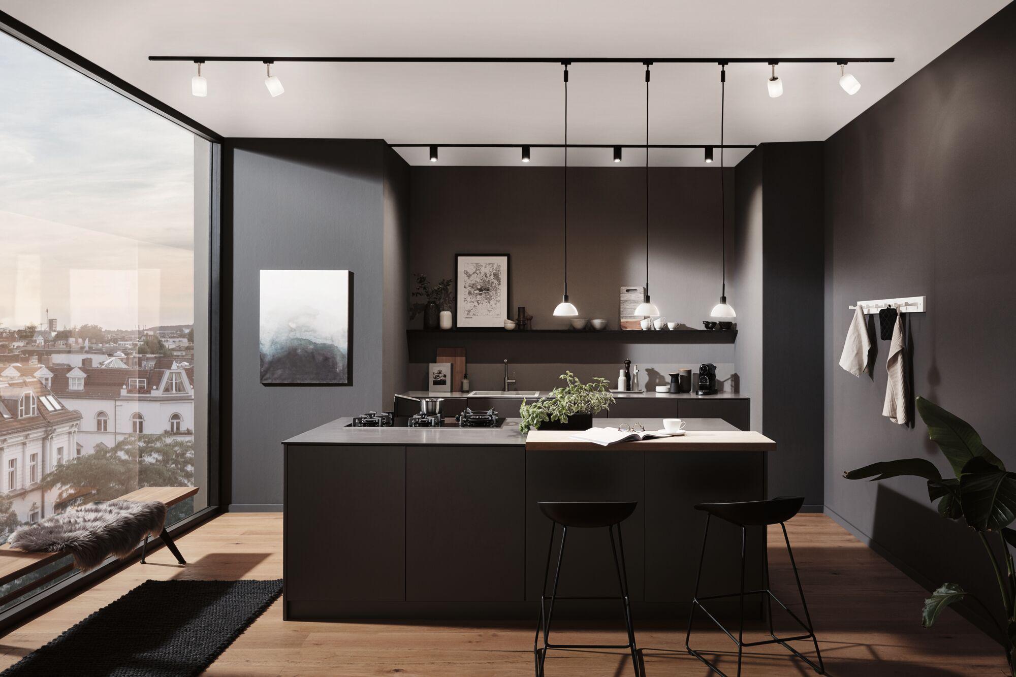Moderne køkken med sort ø, træbordplade og minimalistisk LED-skinnebelysning.