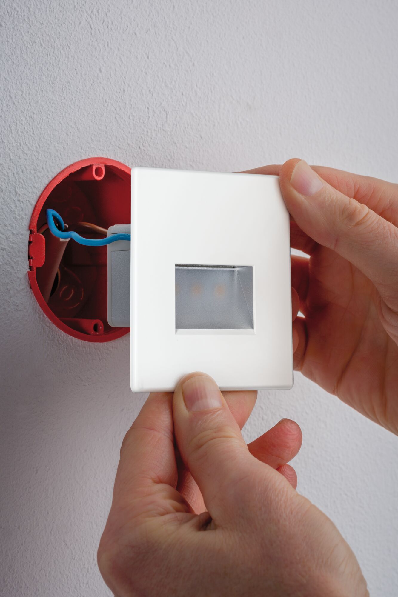 White LED wall recessed light made of plastic being installed in red flush-mounted box for modern lighting