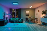 Moderne woonkamer met paarse en warmwitte LED-plafondlampen, bank en houten eettafel