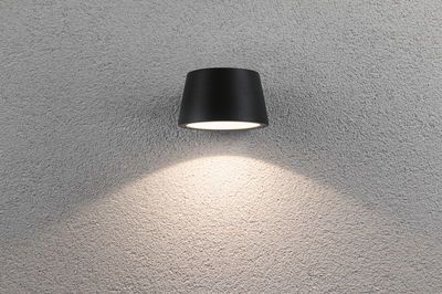 Schwarze Aluminium-Wandleuchte mit warmweißem LED-Licht an grauer Strukturwand für moderne Innenbeleuchtung
