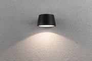 Schwarze Wandlampe aus Metall mit nach unten gerichtetem Licht auf grauer Strukturwand für Innenbeleuchtung