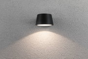 Schwarze Wandlampe aus Metall mit nach unten gerichtetem Licht auf grauer Strukturwand für Innenbeleuchtung