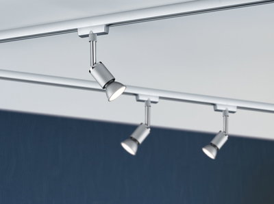 Drei silberne LED-Strahler aus Metall an Schienensystem vor weißer Decke und blauem Hintergrund