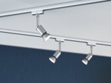 Three silver metal LED spotlights on track system against white ceiling and blue background