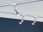 Drei silberne LED-Strahler aus Metall an Schienensystem vor weißer Decke und blauem Hintergrund