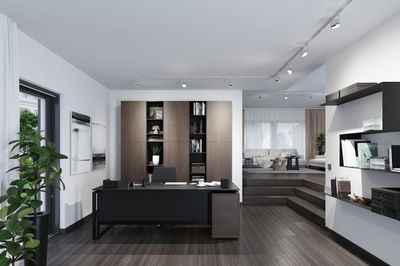 Modernes Büro mit schwarzem Schreibtisch, braunem Holzregal und LED-Schienenbeleuchtung für Arbeitsräume.