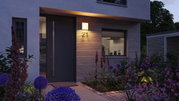 Modern house facade with grey door, wooden cladding and warm white outdoor wall light at dusk