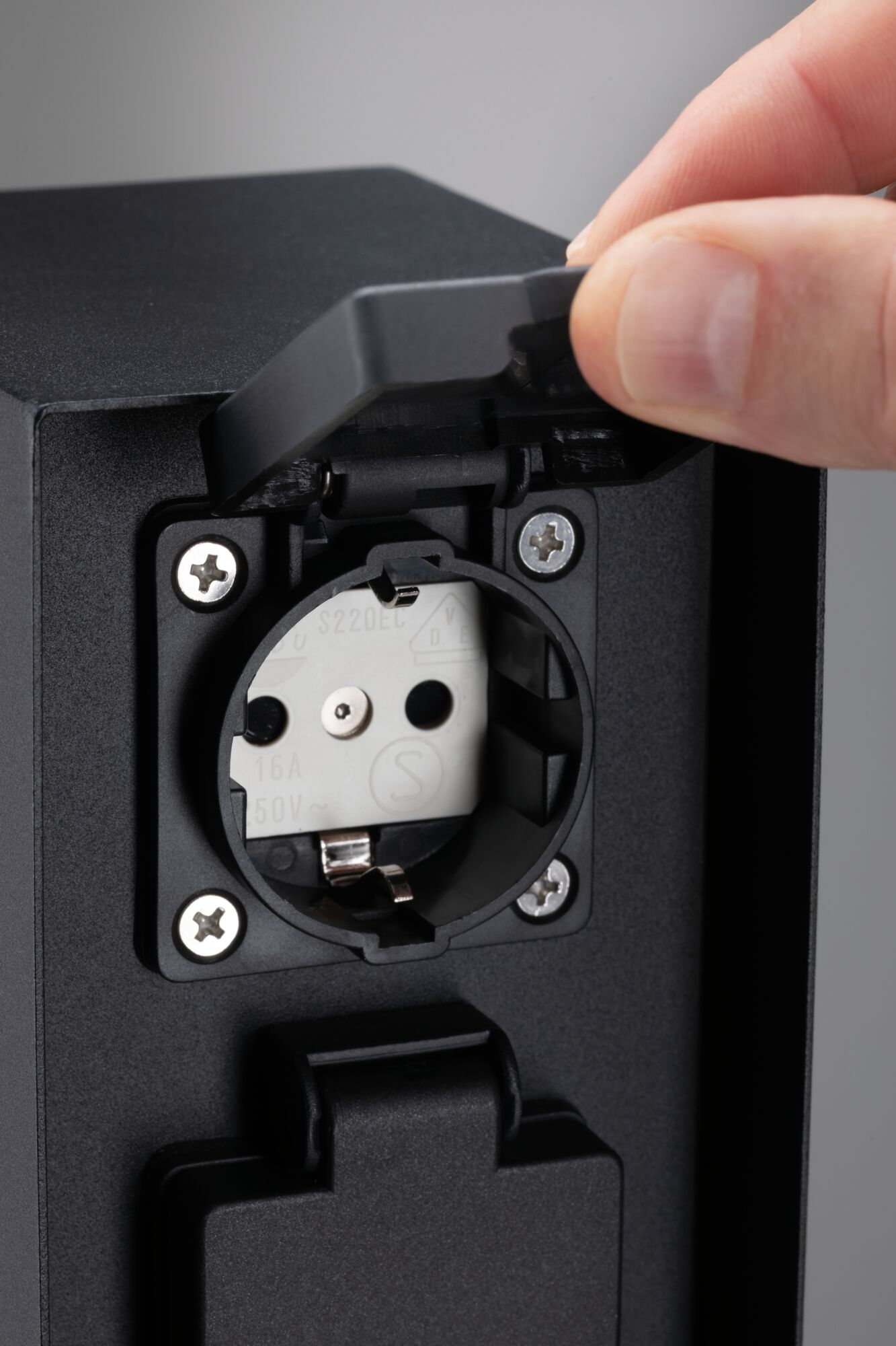 Black plastic socket with protective cover, grounded outlet suitable for outdoor use