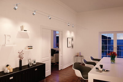 Moderner weißer Seilstrahler mit fünf Spots in elegantem Wohnzimmer mit Holzboden und weißen Möbeln