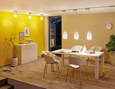 Salle à manger moderne avec chaises blanches, table et suspensions LED blanc chaud sur rail