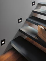 Modern black LED stair lights mounted on wall with warm white light and motion sensor for safety.