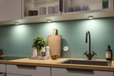 Plan de travail de cuisine moderne en bois avec évier en acier inoxydable et éclairage LED sous les meubles.
