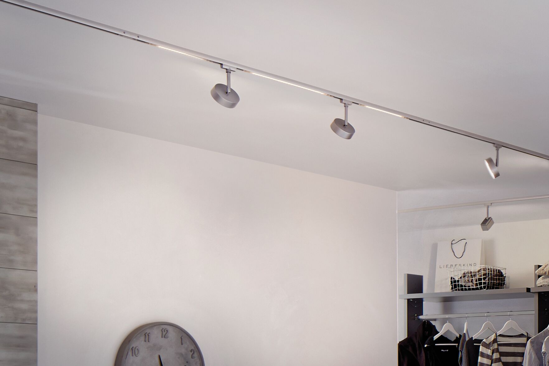 Moderne LED-Schienenbeleuchtung in Silber mit verstellbaren Spots in einem minimalistischen Raum.