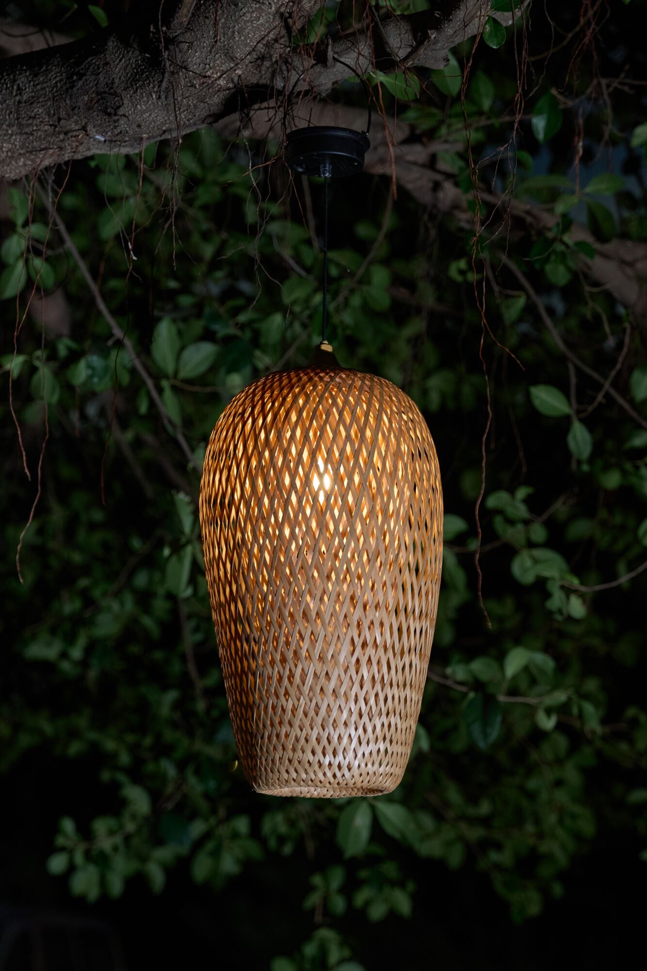 Hanging lamp made of woven natural material in brown with warm light for garden lighting