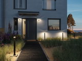 Éclairage extérieur moderne avec lampes LED noires le long du chemin et appliques murales sur maison.