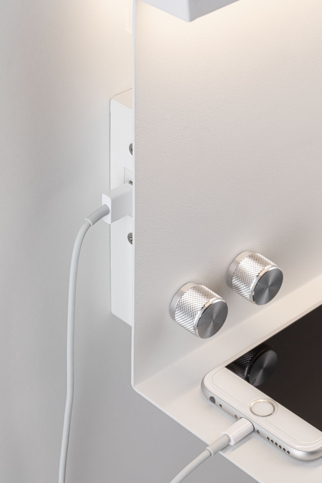Witte wandlichtschakelaar met twee zilveren draaiknoppen en aansluiting voor smartphone-oplaadkabel.