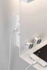 White wall light switch with two silver rotary knobs and smartphone charging cable connection.